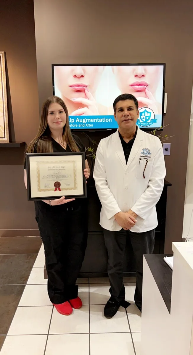 BC Medical graduate holding their framed certificate with their instructor at the Coquitlam campus