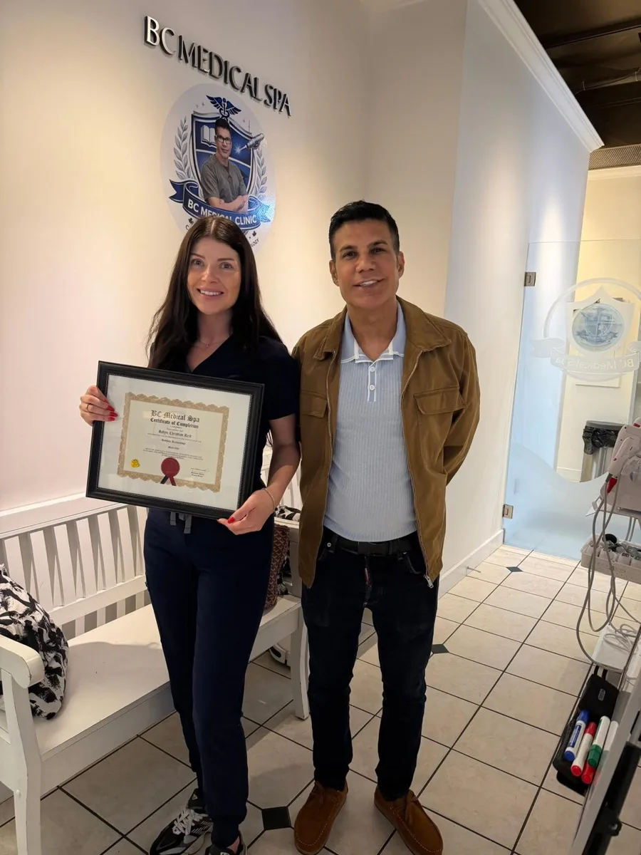 BC Medical graduate holding their framed certificate with their instructor at the Coquitlam campus
