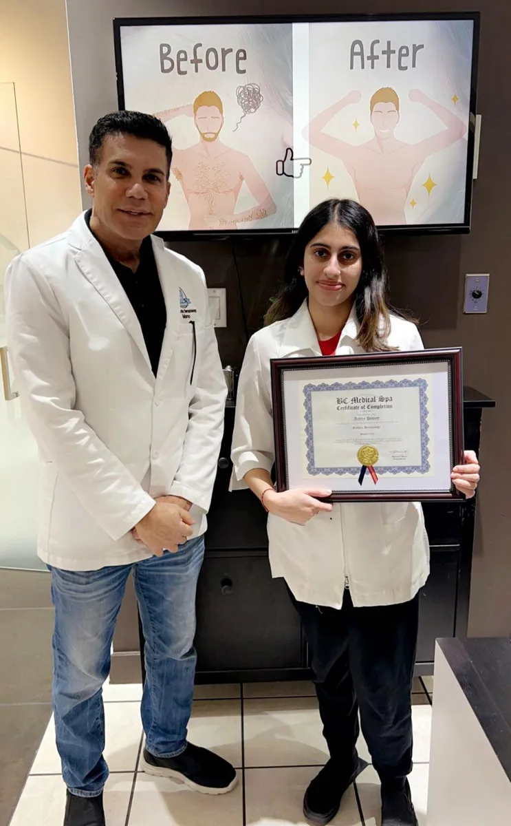 BC Medical graduate holding their framed certificate with their instructor at the Coquitlam campus