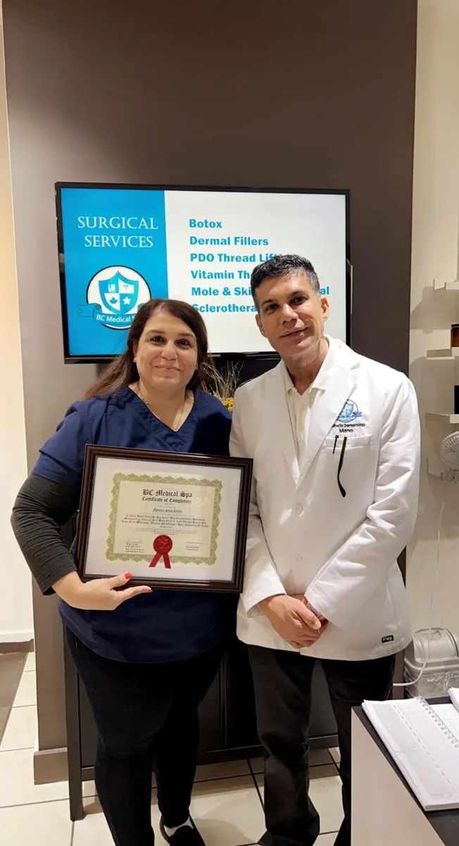 BC Medical graduate holding their framed certificate with their instructor at the Coquitlam campus