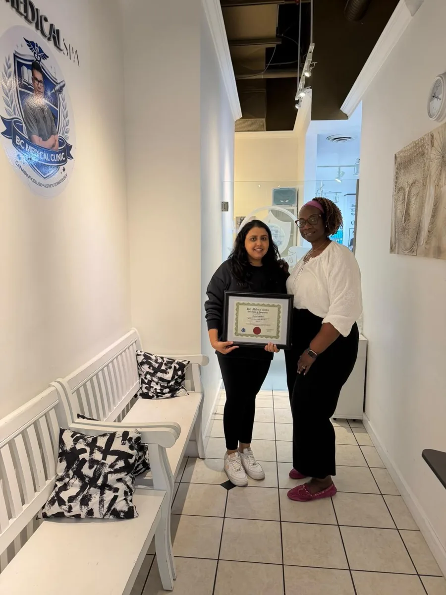 BC Medical graduate holding their framed certificate with their instructor at the Coquitlam campus