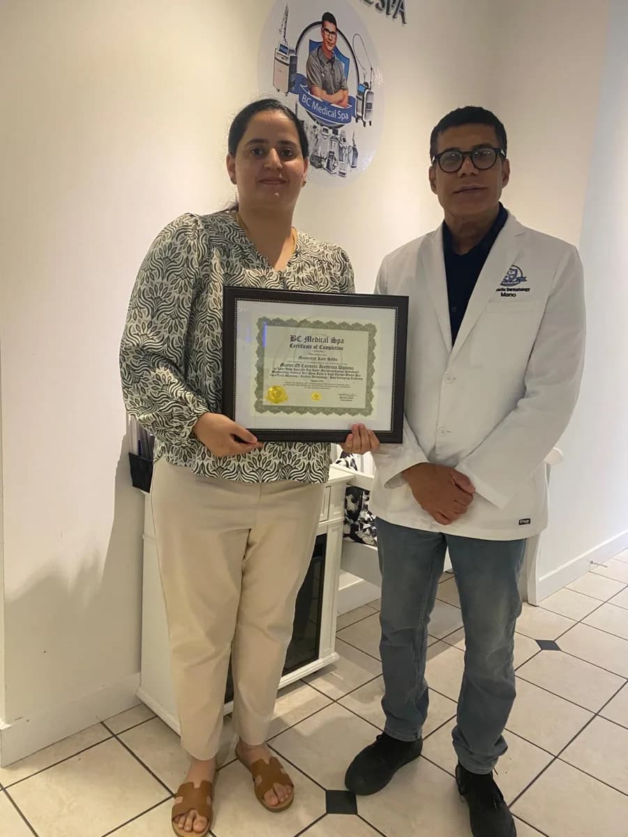 BC Medical graduate holding their framed certificate with their instructor at the Coquitlam campus