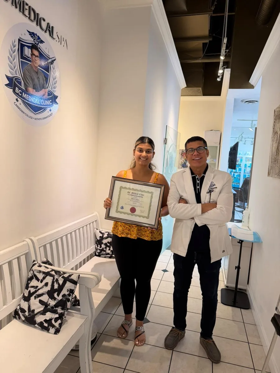 BC Medical graduate holding their framed certificate with their instructor at the Coquitlam campus